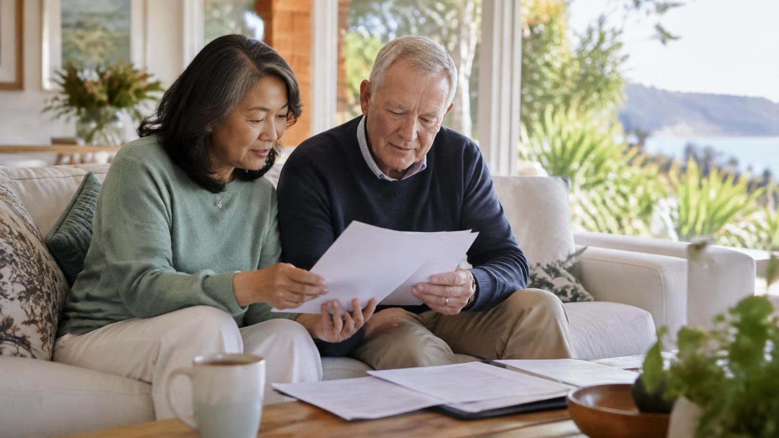 New Zealand woman reading a health insurance price increase letter at the kitchen bench of a bright Kiwi home