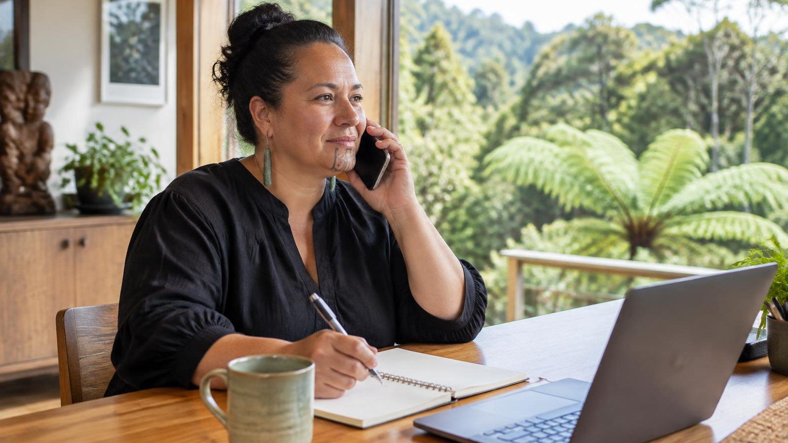 New Zealand adviser helping a couple reduce their health insurance premium at a timber table with native plants in the background